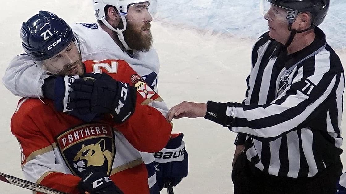 Hockey referee separating two players during a game between Panthers and Lightning